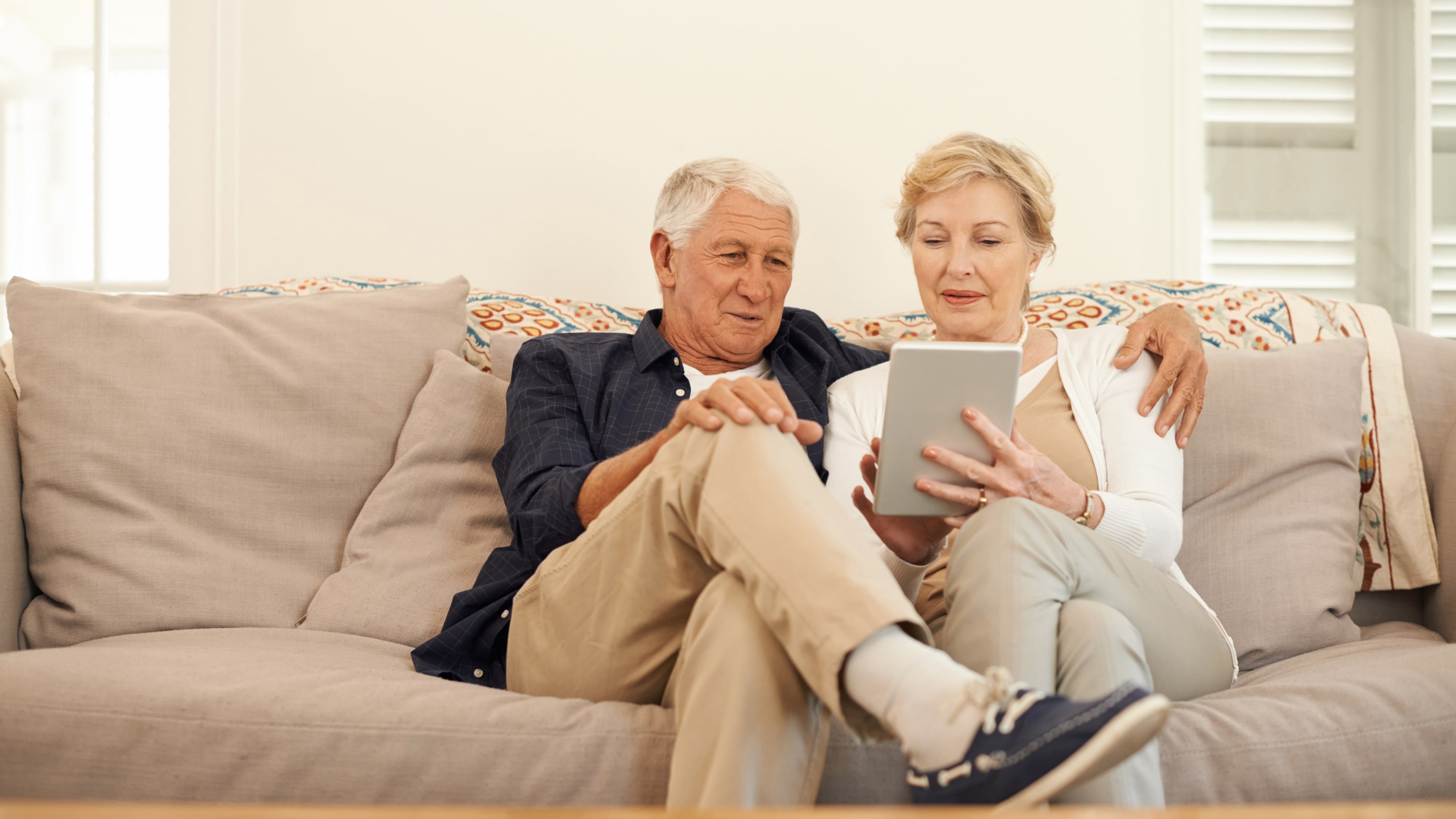 An older couple researching mobility aids on their smart device.