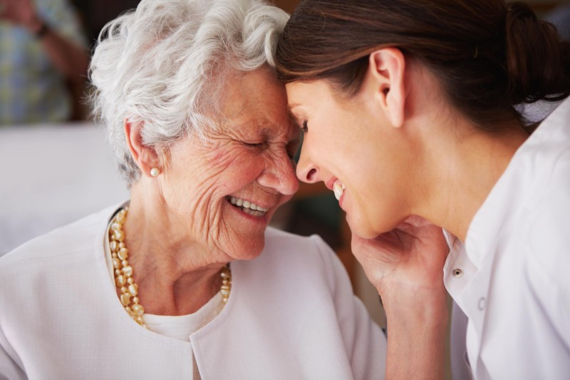 A caregiver bumping foreheads with an older loved one