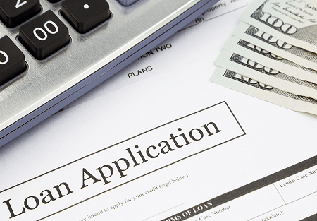 A loan application, calculator, and five hundred dollar bills