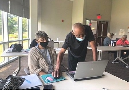 Two older adults participating in the technology training program