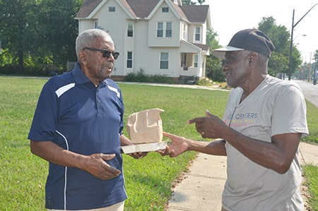 Rose Centers for Aging Well Home-Delivered Meals driver/jumper handing home-delivered meal participant their lunch