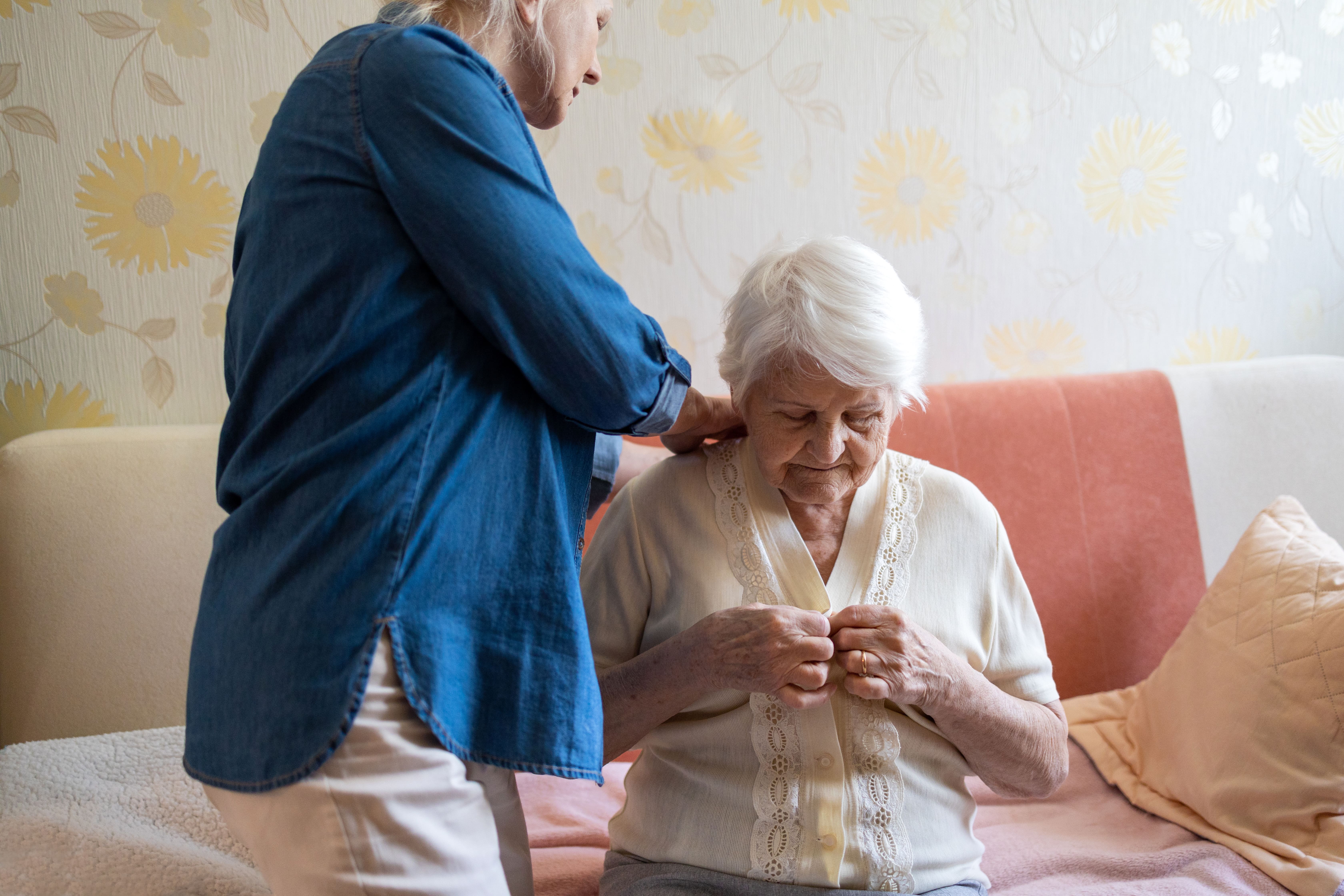 A caregiver helping an older adult get dressed