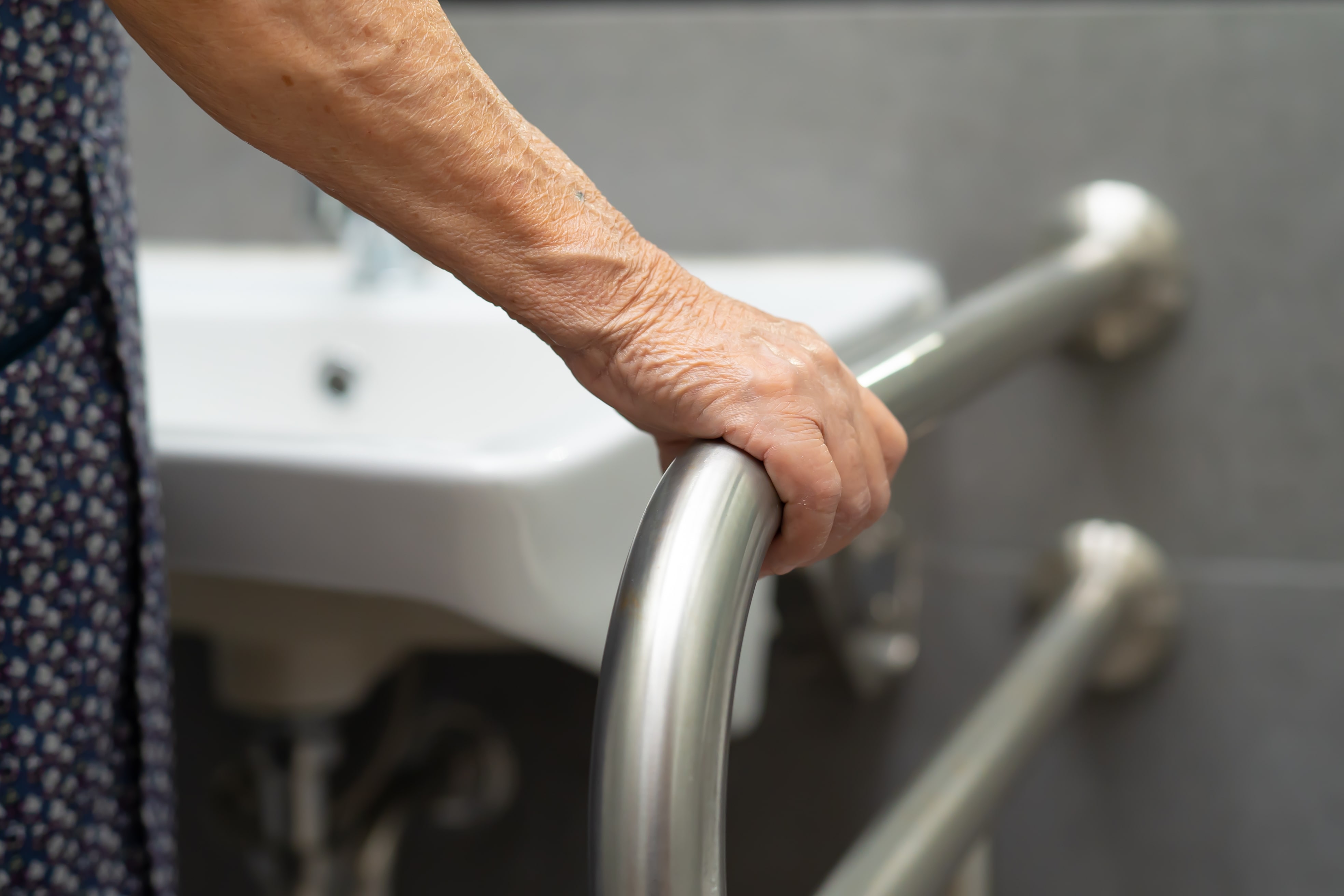 An older adult using a bathroom grab bar