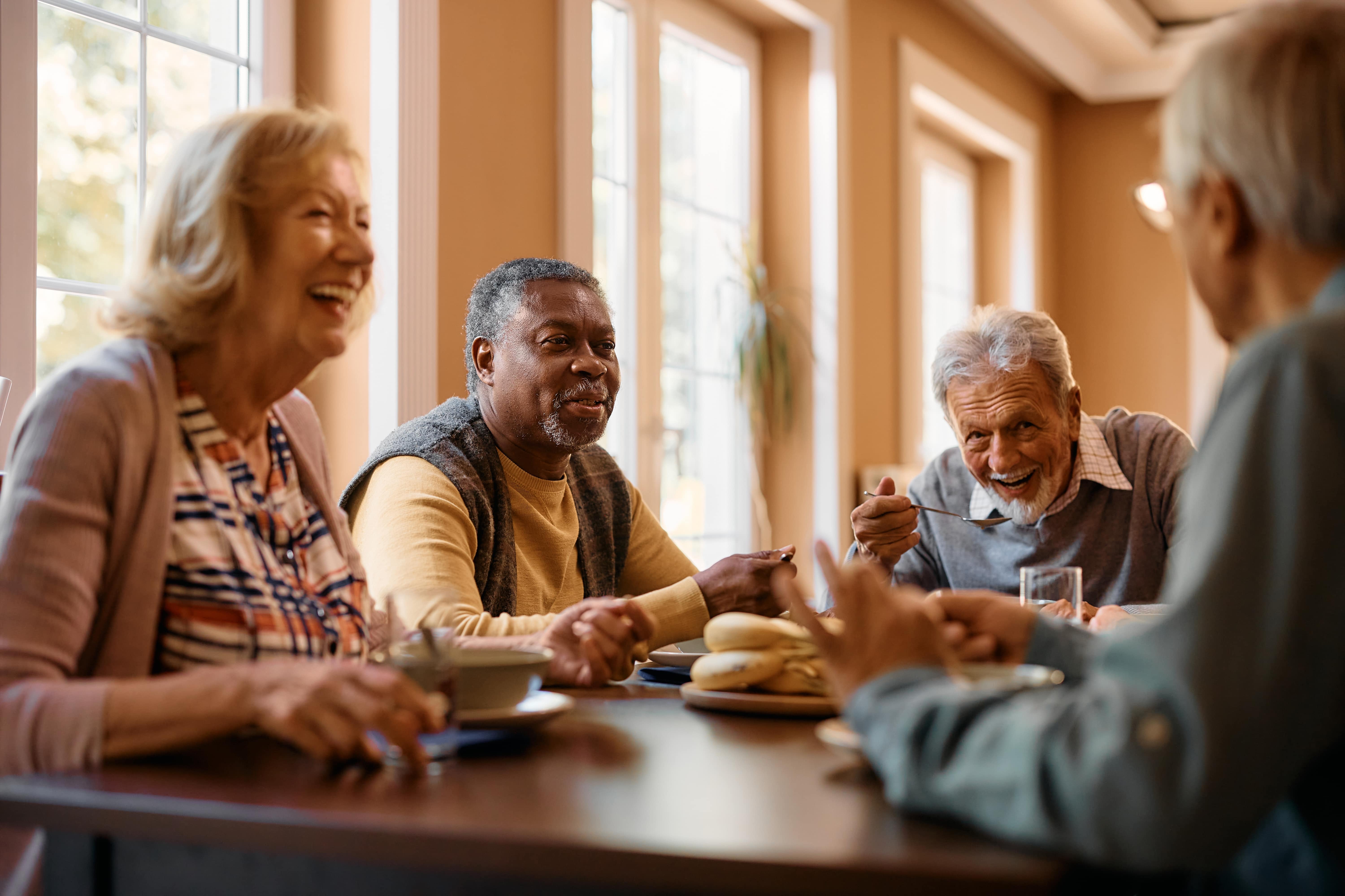 Four older adults socializing over breakfast at a restaurant