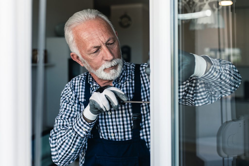 An older adult doing maintenance on his house