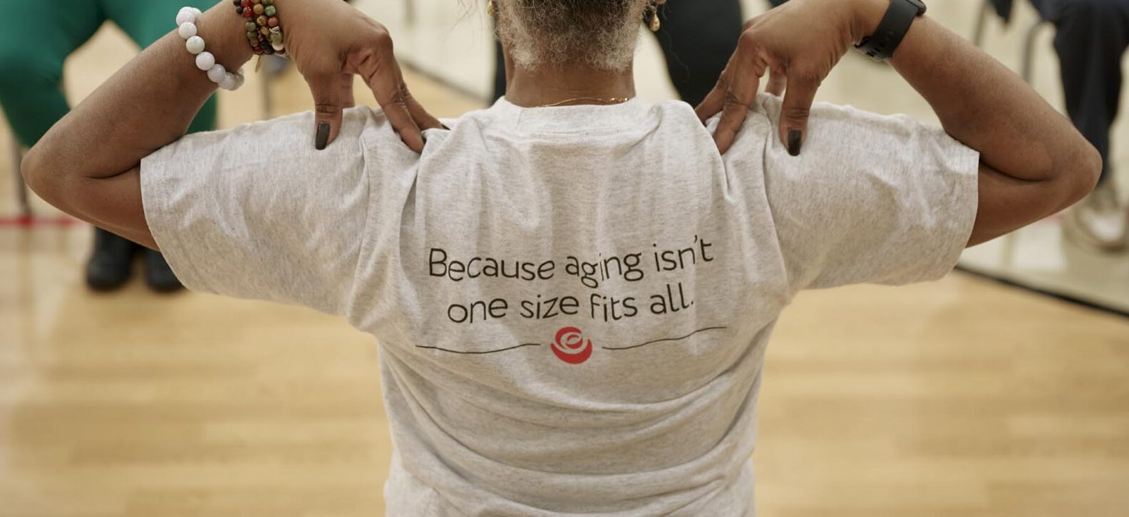 A Benjamin Rose employee running an exercise class for seniors. The back of her shirt says "Because aging isn't one size fits all."