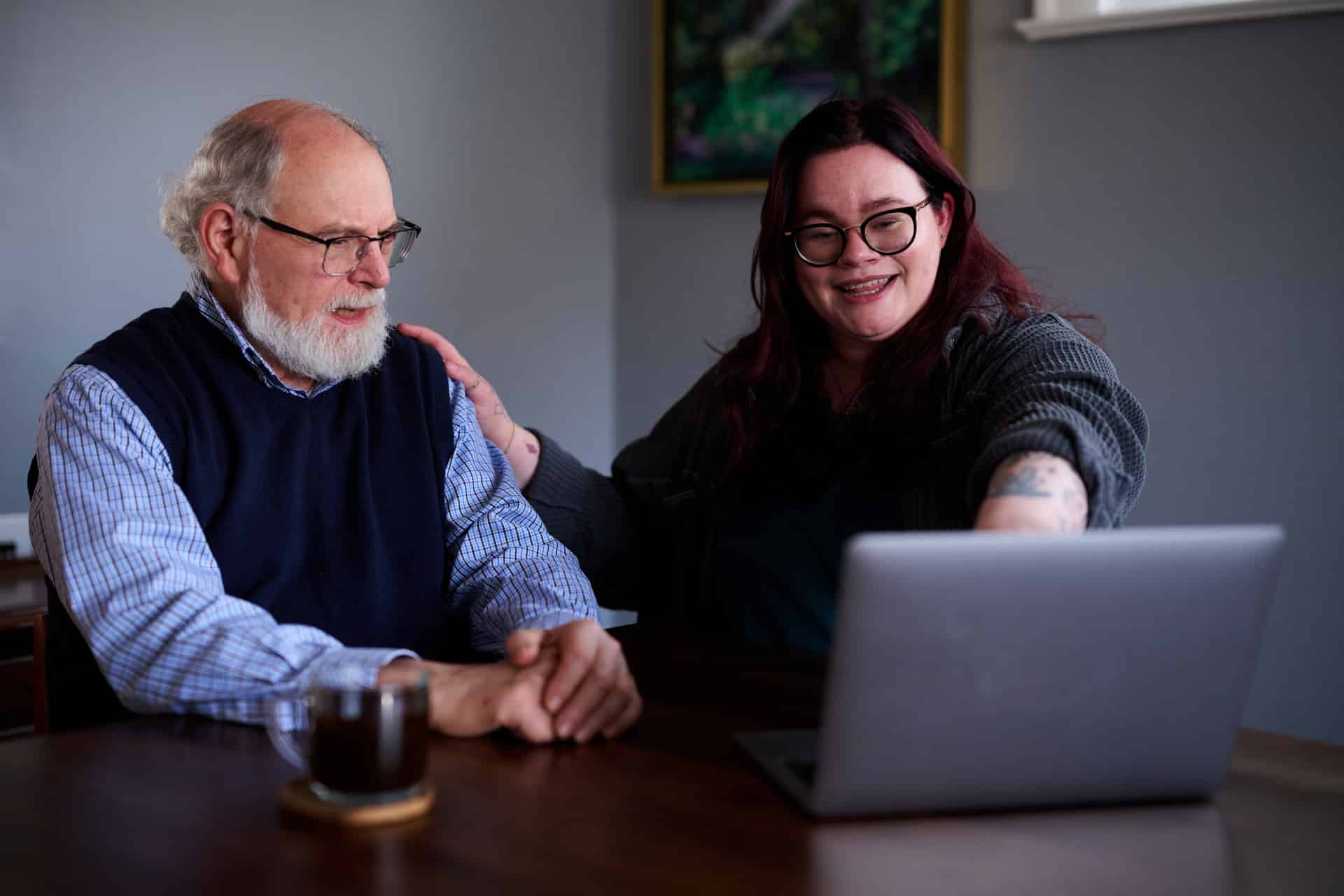A caregiver showing an older adult something on a computer screen