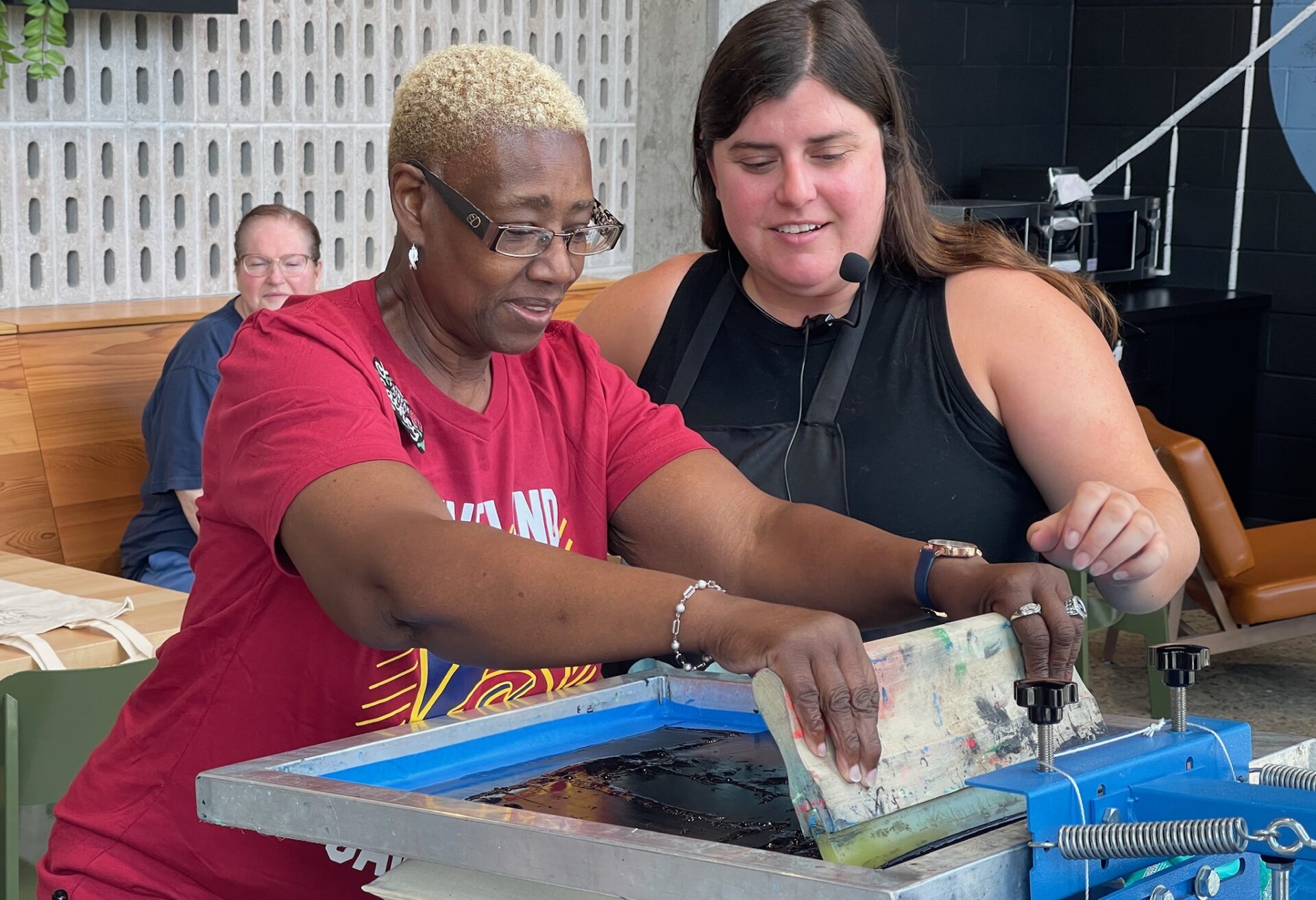 A Rose on the Go participant screen printing a bag with the help of staff